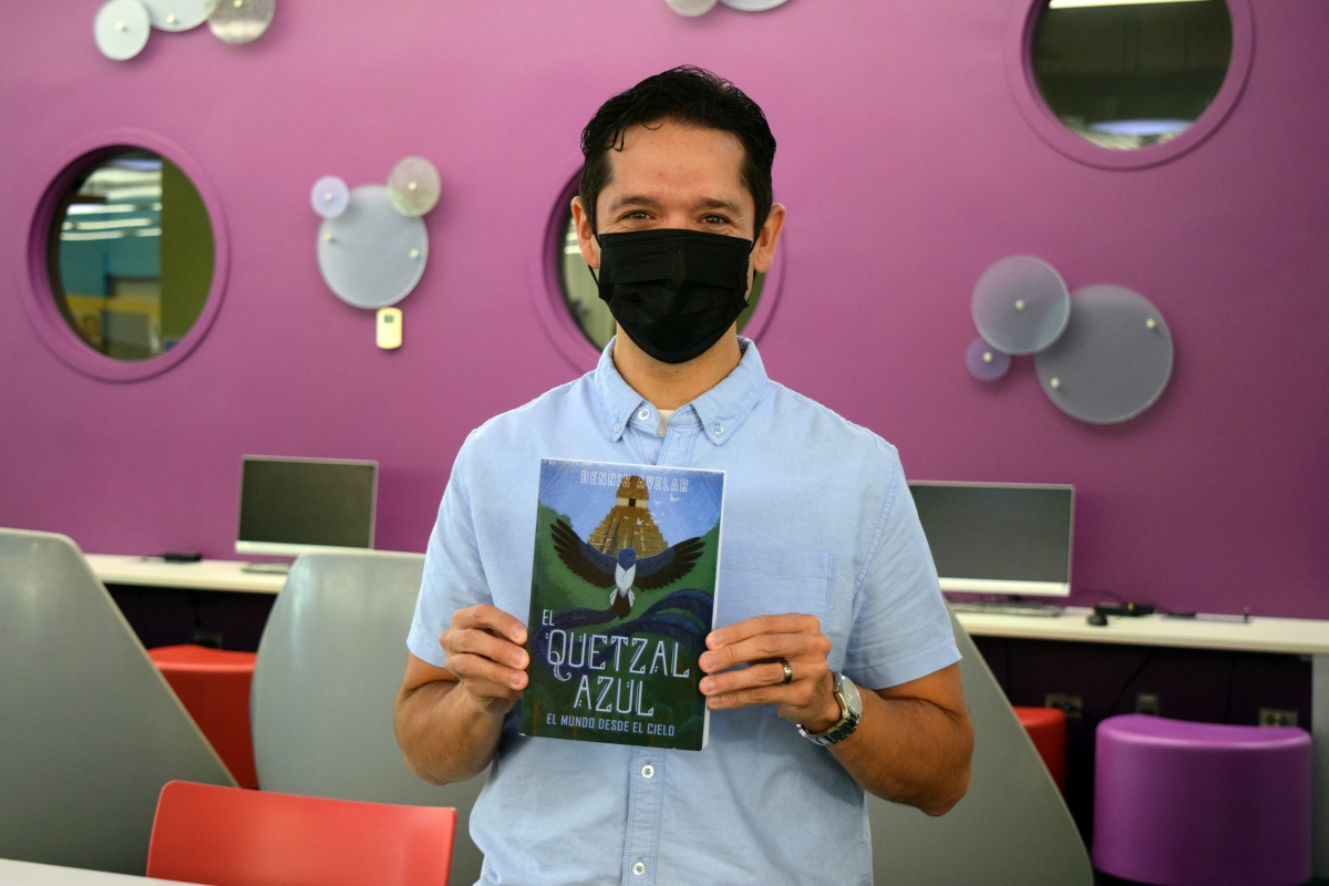 Dennis Avelar poses with his book at the library