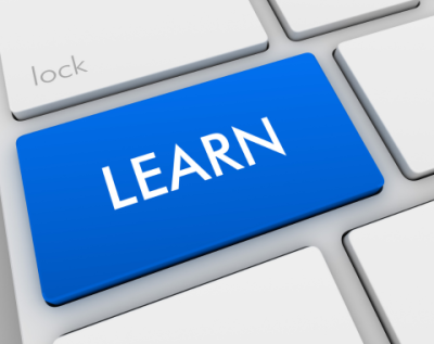 close up shot of a white and gray computer keyboard with one large blue keyboard key with the text "LEARN"