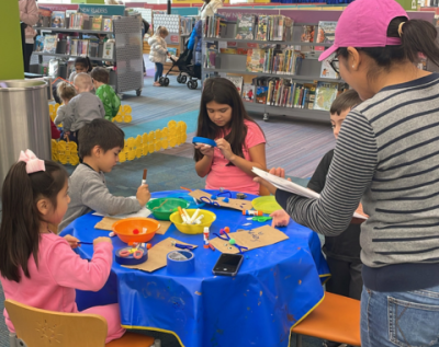 a group of children and an adult participating in a craft at a table