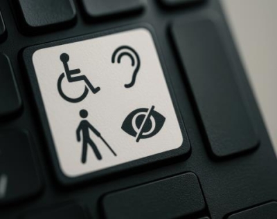 Photo shows one white key on a black keyboard. The white key has icons for wheel chair, hearing aid, walking cane for visually impaired, and icon for blind. 