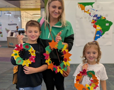 adult and two children holding up paper fall leaf crafts