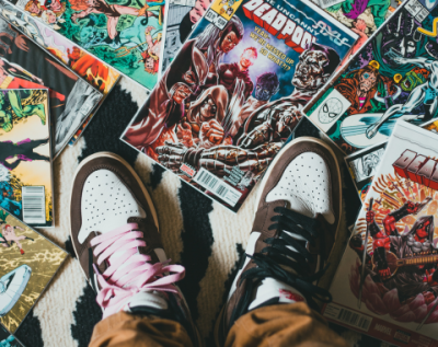looking down at a pair of white and black sneakers with a variety of comics surrounding them