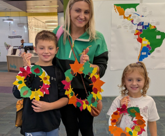 adult and two children holding up paper fall leaf crafts