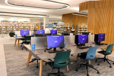 two rows of 3 desktop computers in a bright area with shelves of books in the background
