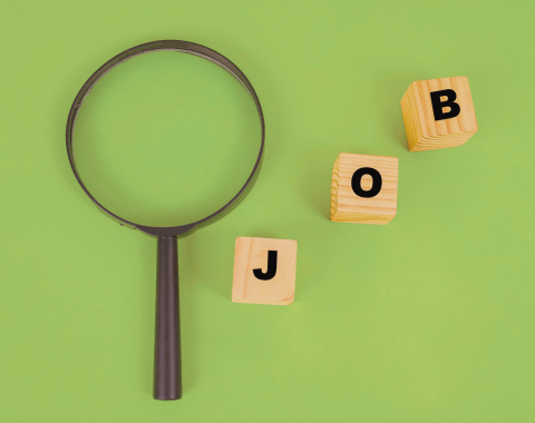 a magnifying glass next to three small wooden blocks with the letters "J" "O" "B"