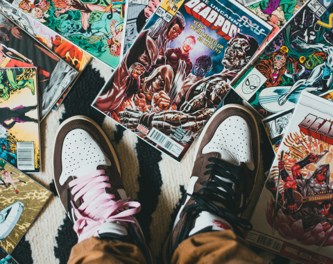looking down at a pair of white and black sneakers with a variety of comics surrounding them
